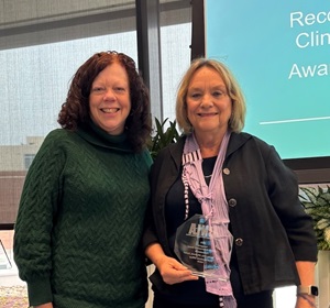 Joan Stanley holding the CNLA Lifetime Achievement Award, standing next to another person