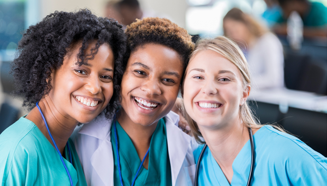 Three healthcare workers smile at the camera